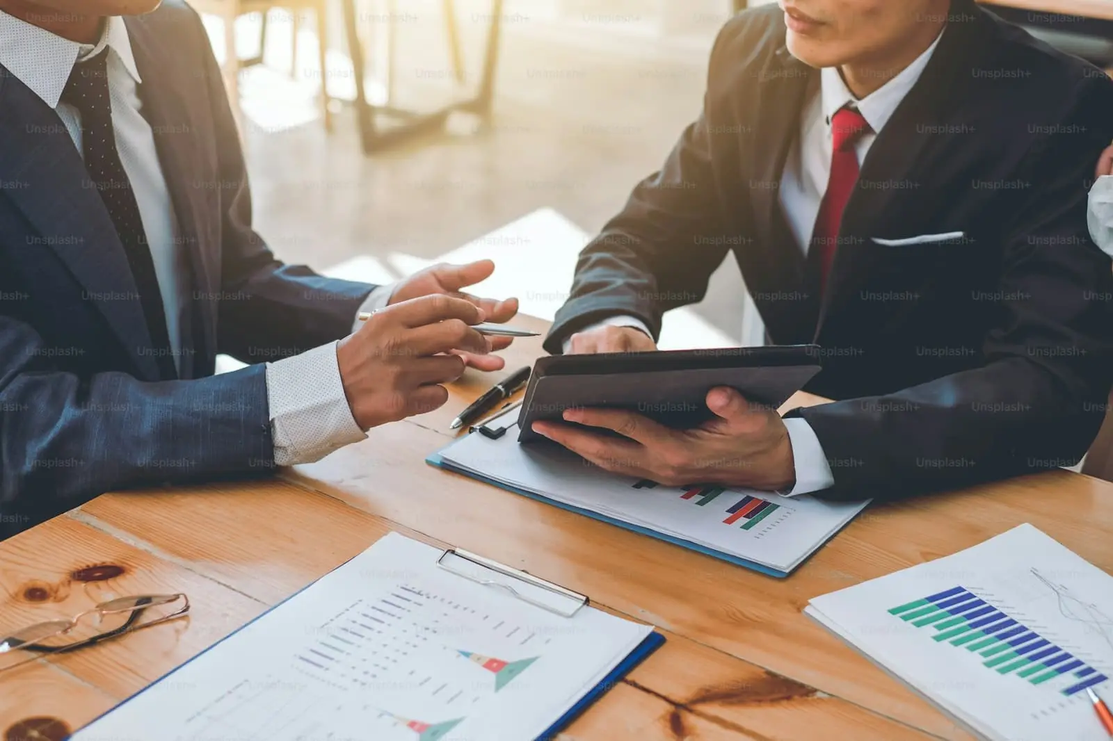 Businessman using a tablet while discussing finance options in a meeting