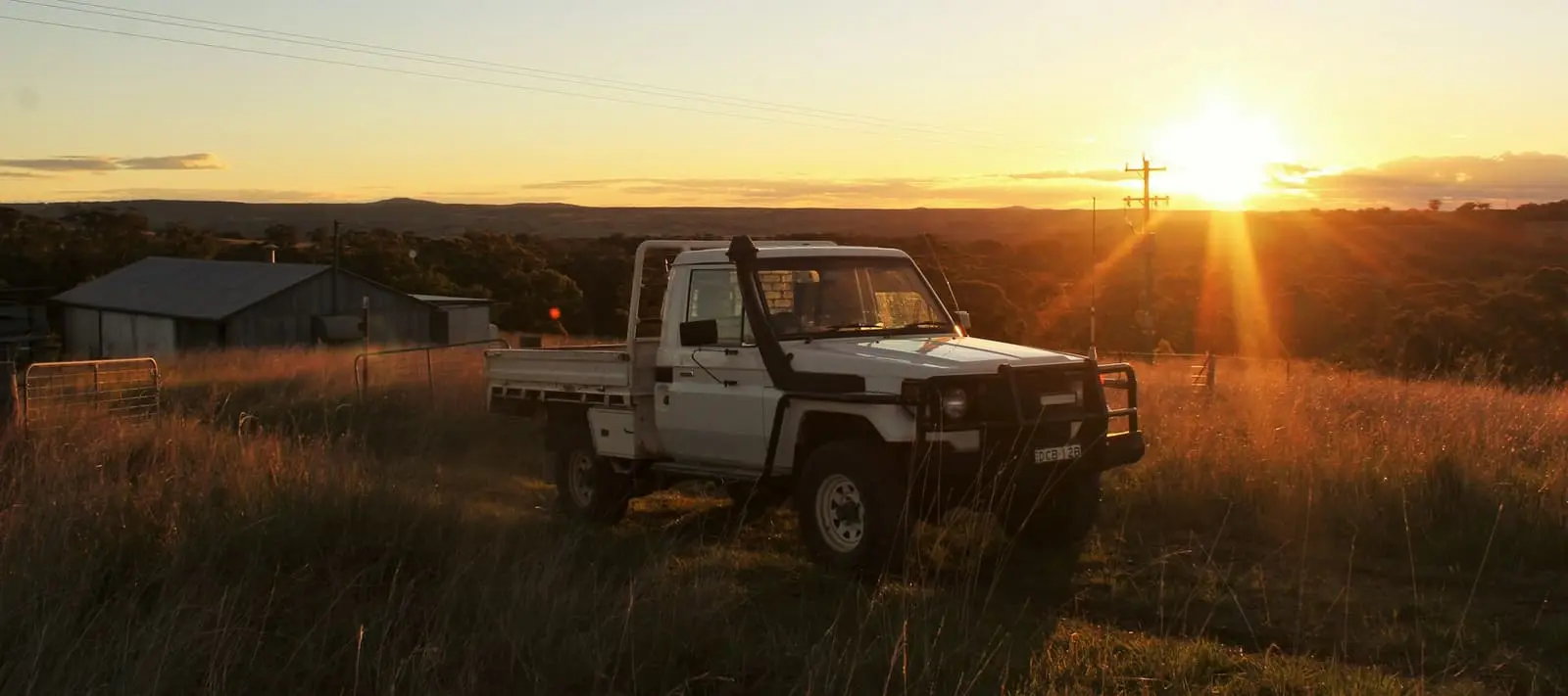 Farmer with ute near dam at sunset