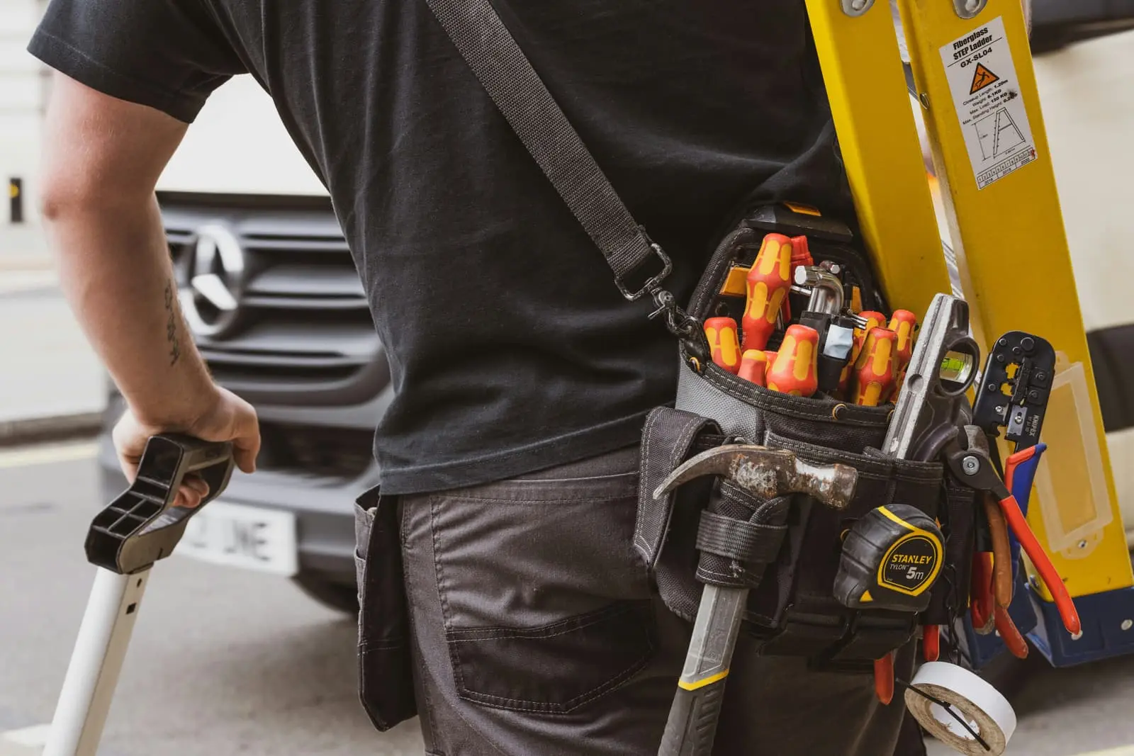 Tradesman in a black shirt holding a black and yellow power tool