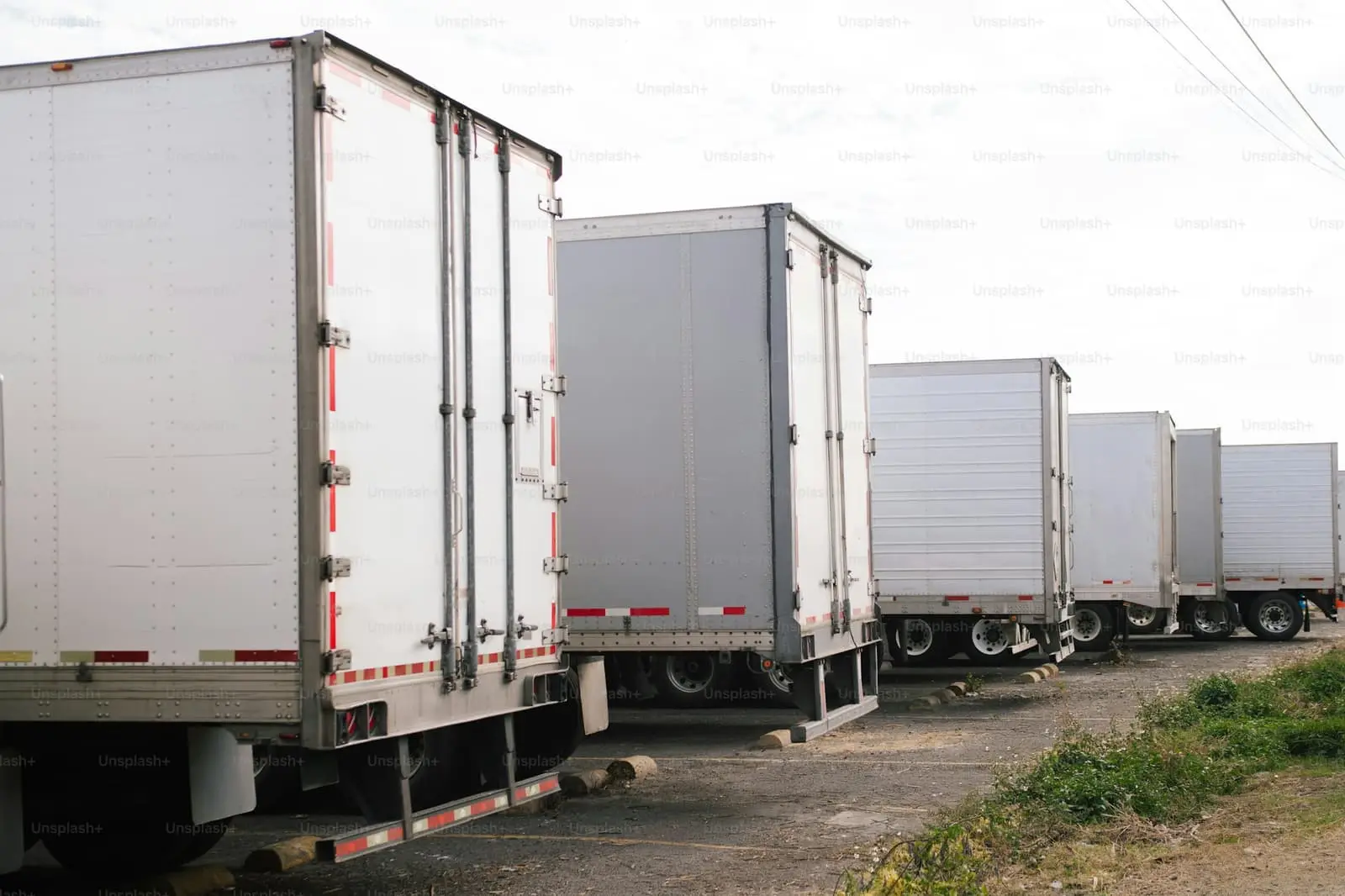 Several white semi-trailer prime movers parked in a neat row at a transport depot